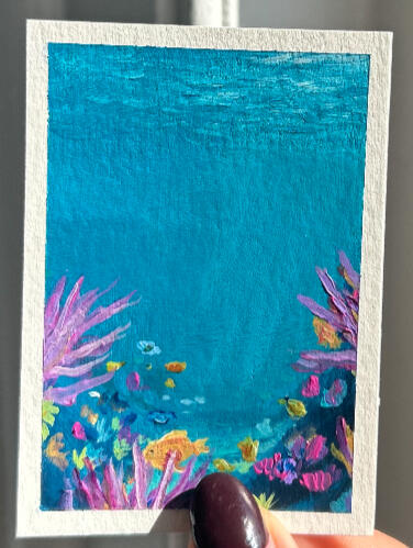 sold underwater aceo painting on paper, showing underwater scene, colourful fish and corals. painting is showed held by hand.
