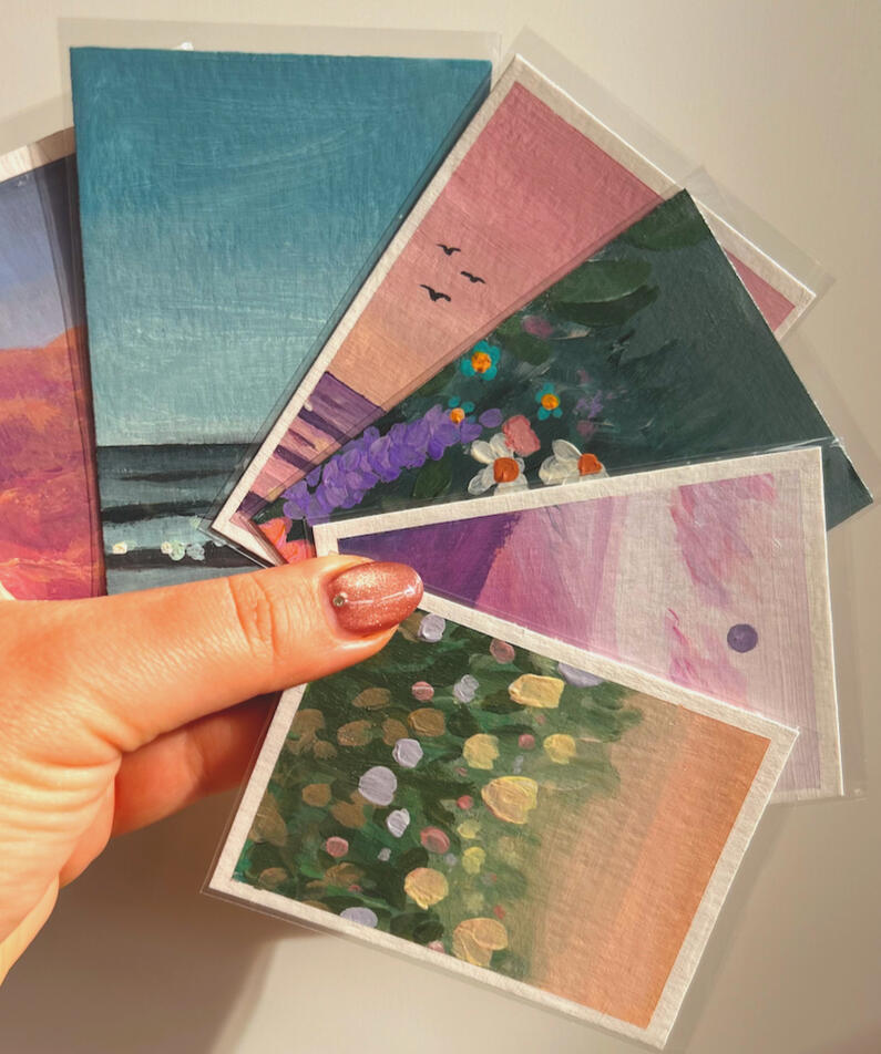 hand holding 6 different aceo paintings in their protective sleeves