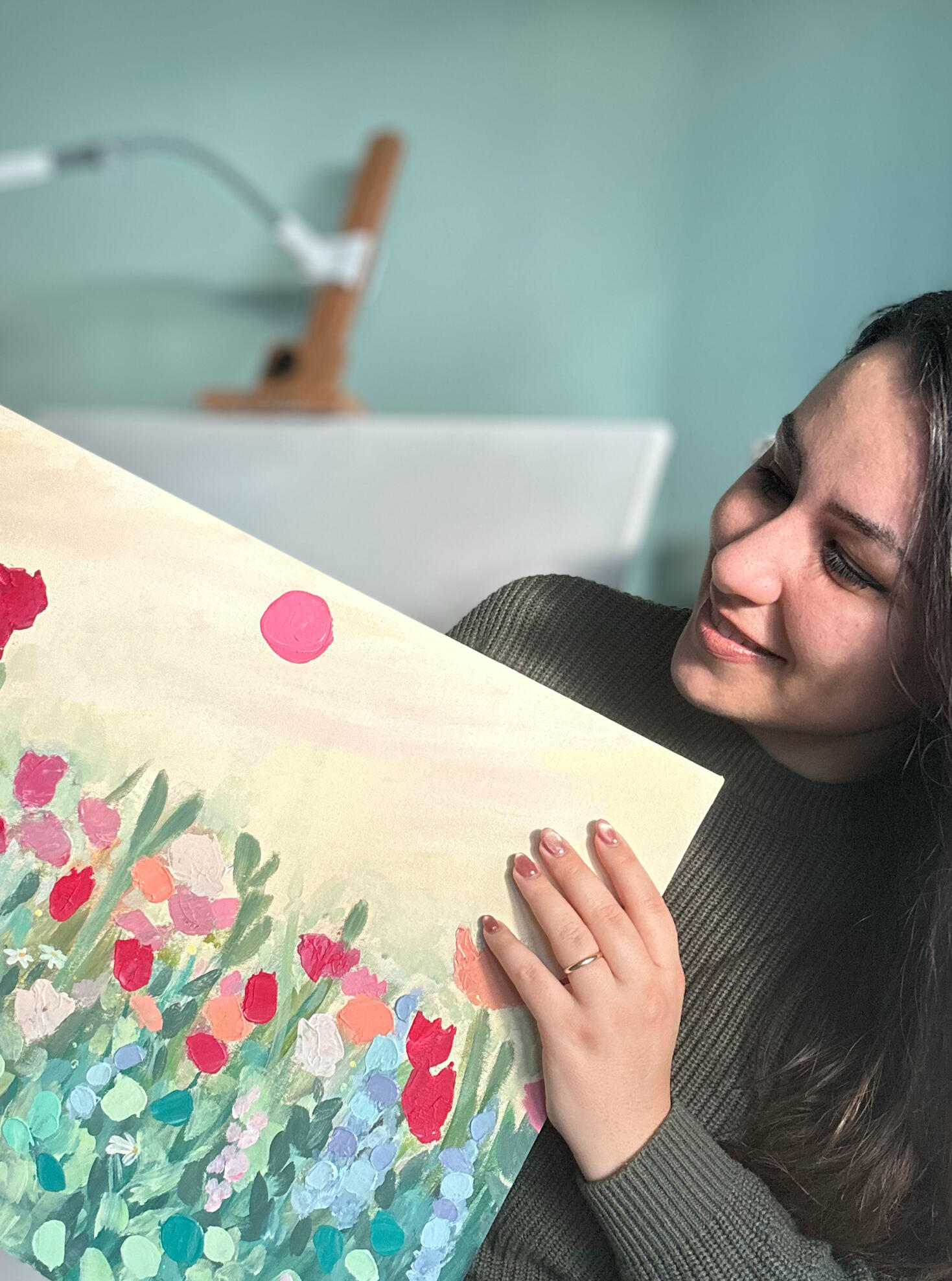 artist Giulia holding a floral textured painting on canvas panel